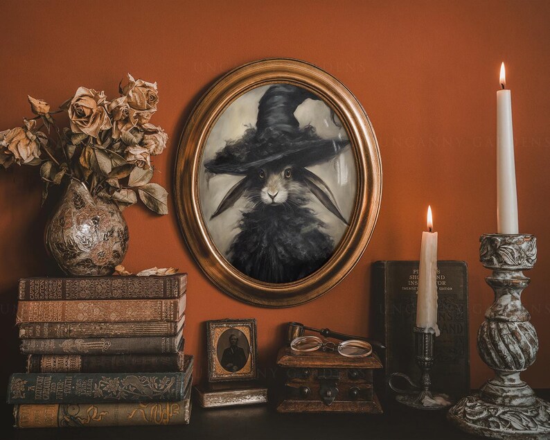 May include: A framed portrait of a black rabbit wearing a witch's hat, set against a dark red wall with candles and books.
