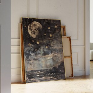May include: A framed canvas print with a dark blue background featuring a large, full moon and gold stars. The moon is in the center of the image and the stars are scattered around it. The canvas has a textured, abstract look.