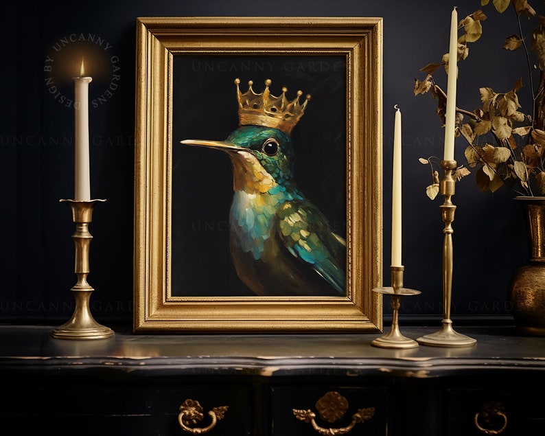 May include: A painting of a green and blue hummingbird wearing a gold crown. The painting is framed in a gold frame and is hanging on a dark wall. There are two candlesticks with lit candles on either side of the painting.