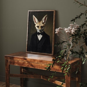 May include: A framed portrait of a fox in a tuxedo and bow tie. The artwork has a vintage aesthetic, with the fox's face and ears prominently displayed. The frame is a warm brown, and the background is a dark, muted tone.