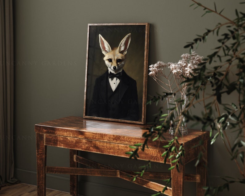 May include: A framed portrait of a fox in a tuxedo and bow tie. The artwork has a vintage aesthetic, with the fox's face and ears prominently displayed. The frame is a warm brown, and the background is a dark, muted tone.
