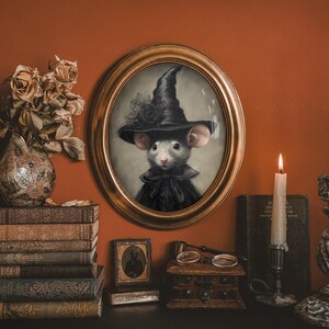 May include: A framed portrait of a mouse wearing a black witch hat and a black dress. The portrait is set against a brown wall with a vase of dried flowers, books, and candles.