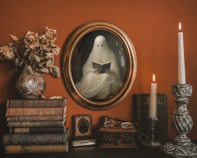 May include: An oval framed portrait of a ghost reading a book, with two black eyes. The image is surrounded by lit candles, antique books, a vase of dried flowers, and a small framed photograph. The scene is set against a burnt orange wall.