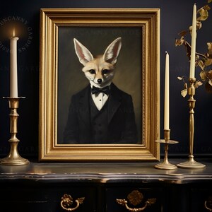 May include: A framed portrait of a fox in a tuxedo and bow tie. The artwork is in a gold frame, and the scene is set on a dark surface with lit candles in gold candle holders. The text "UNCANNY GARDENS" is visible on the frame.