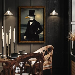 May include: A black and white painting of a seagull wearing a top hat and a tuxedo, standing on a beach with the ocean in the background. The painting is framed in gold and hanging on a dark wall.