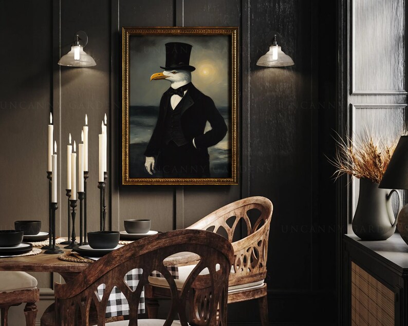 May include: A black and white painting of a seagull wearing a top hat and a tuxedo, standing on a beach with the ocean in the background. The painting is framed in gold and hanging on a dark wall.