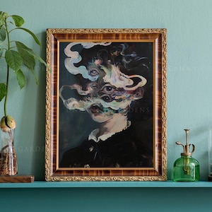 May include: A framed artwork with a surreal portrait. The painting features a figure with multiple eyes and swirling, smoky forms in shades of blue, white, and pink. The frame is ornate with a gold finish. The artwork is displayed on a teal shelf.