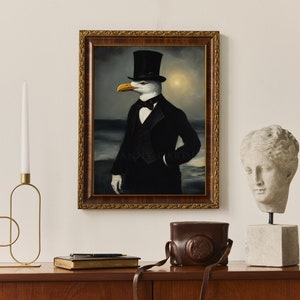 May include: A framed painting of a seagull wearing a top hat and a tuxedo, standing in front of a stormy sea. The painting is in a gold frame and is hanging on a white wall.