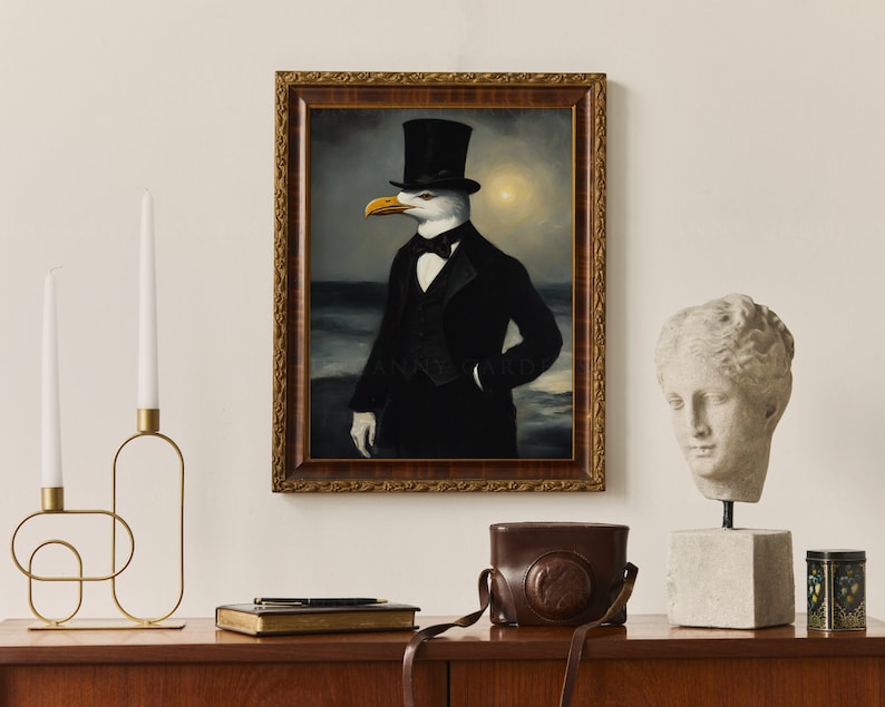 May include: A framed painting of a seagull wearing a top hat and a tuxedo, standing in front of a stormy sea. The painting is in a gold frame and is hanging on a white wall.