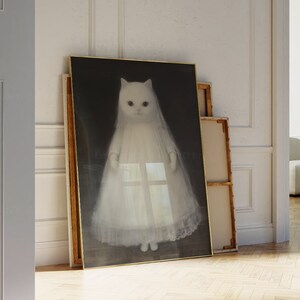May include: A framed print of a white cat wearing a white dress, standing against a dark background.