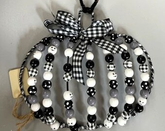 May include: Black and white beaded pumpkin wreath with a black and white checkered ribbon. The beads are in a variety of shapes and sizes, including polka dots and ghost faces.