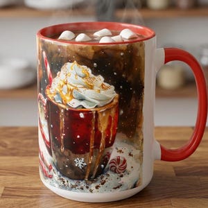 May include: A white ceramic mug with a red rim and handle, featuring a watercolor-style illustration of a steaming mug filled with hot chocolate, whipped cream, caramel drizzle, marshmallows, and peppermint candies on a snowy background.