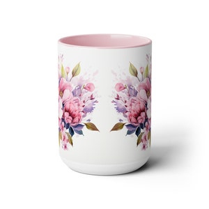 Puede incluir: Taza de cer&aacute;mica blanca con interior rosa y un dise&ntilde;o floral con flores de acuarela rosa, p&uacute;rpura y azul. Las flores est&aacute;n dispuestas en un patr&oacute;n sim&eacute;trico en la taza.