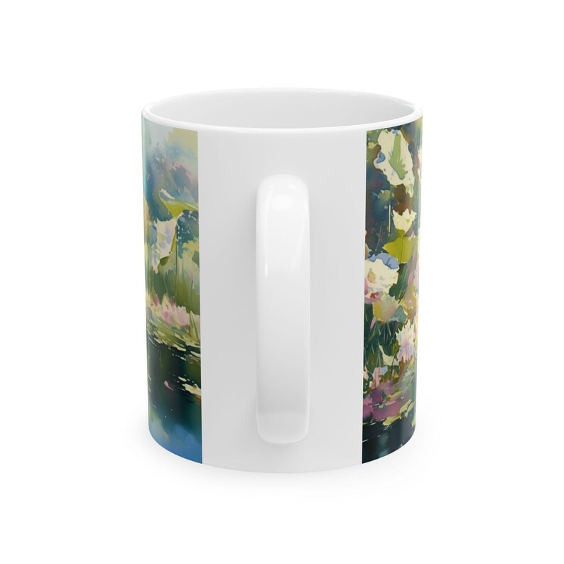 May include: A white ceramic mug featuring a wrap-around watercolor-style print of a pond scene. The artwork displays soft brushstrokes in shades of green, blue, pink, and white, depicting aquatic plants and reflections on the water surface.