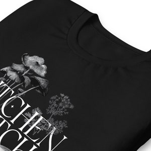 May include: Black t-shirt with a white graphic of mushrooms and a sprig of dill. The text "Shroom Queen" is printed on the shirt.