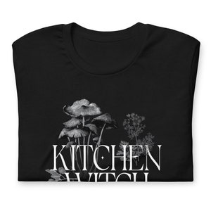 May include: Black t-shirt with a white graphic of mushrooms and the text "Kitchen Witch".
