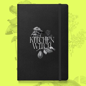 May include: Black journal with the words "KITCHEN WITCH" in white script, accompanied by a botanical illustration of mushrooms, leaves, and a plum. The journal has a black elastic band closure.
