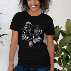 May include: Black t-shirt with a white graphic of botanical illustrations and the text "Kitchen Witch".