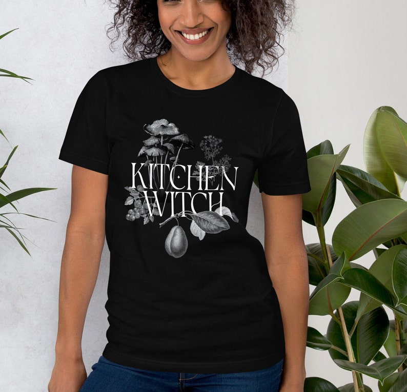 May include: Black t-shirt with a white graphic of botanical illustrations and the text "Kitchen Witch".