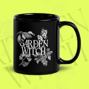 May include: Black ceramic mug with a white graphic design of a butterfly, leaves, and berries. The text "GARDEN WITCH" is printed in white on the mug.