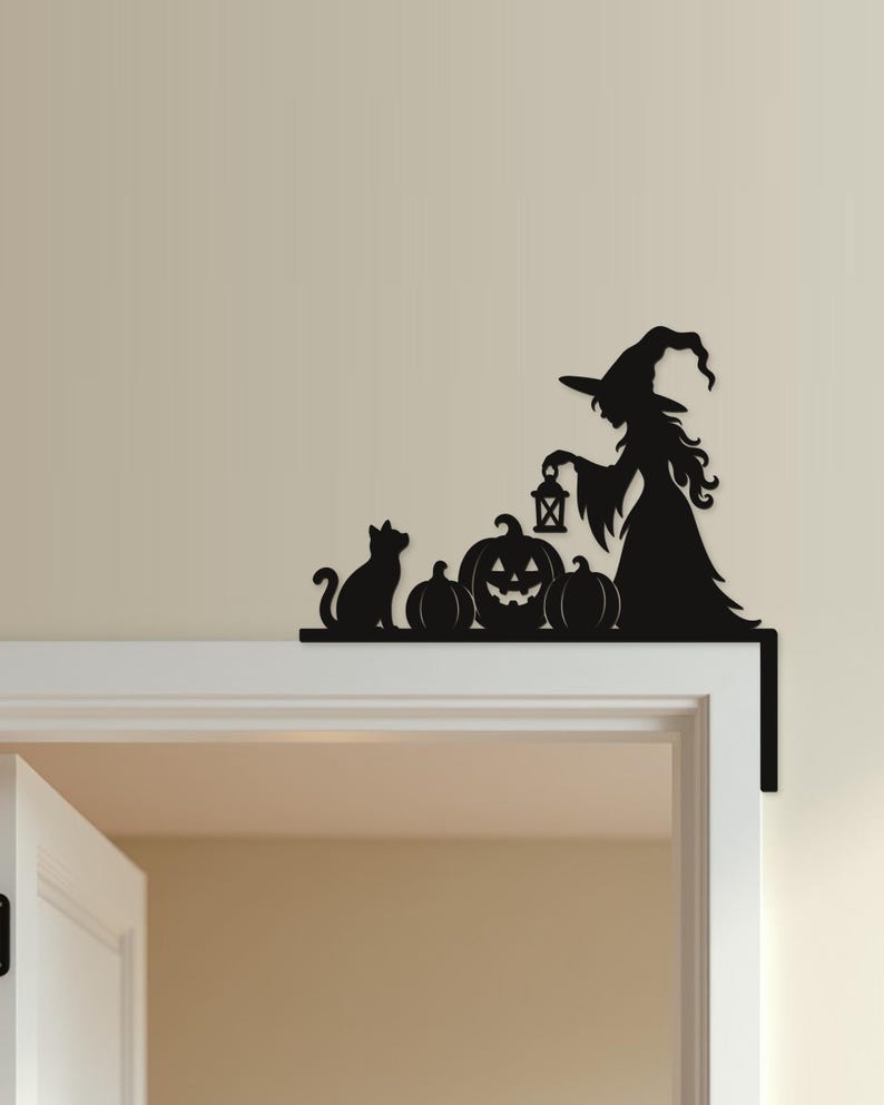 May include: A black metal door corner sign featuring a silhouette of a witch wearing a pointed hat and holding a lantern, accompanied by a cat and three pumpkins, designed to fit onto the top corner of a door frame for decorative display.