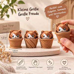 May include: Four brown and white cat figurines in textured pots. Text reads: Kleine Gr&ouml;&szlig;e Gro&szlig;e Freude, Perfekt zum Fidgeten, Sammeln und Verschenken, Good Things Ahead. Dimensions shown are 50 mm (1.97 in) height and 65 mm (2.56 in) width.