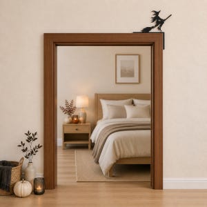 May include: A black metal witch silhouette decoration designed to sit on the top corner of a door frame. The figure depicts a witch riding a broomstick, featuring a pointed hat and flowing cape, crafted as a flat, solid decorative accent piece.