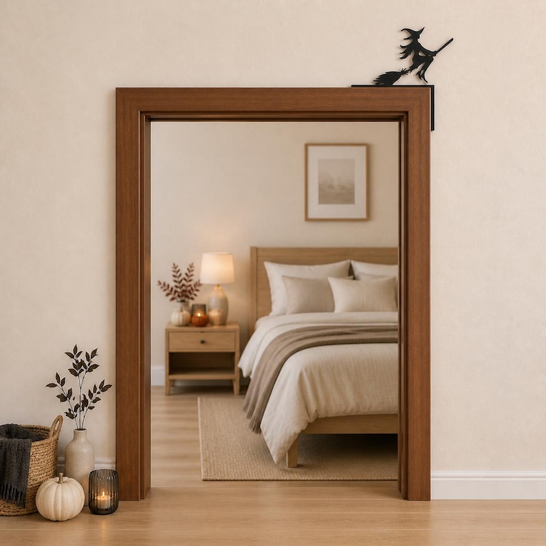 May include: A black metal witch silhouette decoration designed to sit on the top corner of a door frame. The figure depicts a witch riding a broomstick, featuring a pointed hat and flowing cape, crafted as a flat, solid decorative accent piece.
