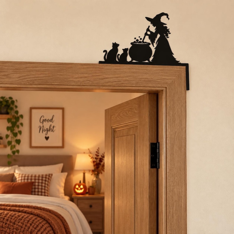 May include: A black metal door corner sign featuring a silhouette of a witch wearing a pointed hat, standing beside a bubbling cauldron and two cats. The decorative piece is designed to be mounted on the upper corner of a door frame.