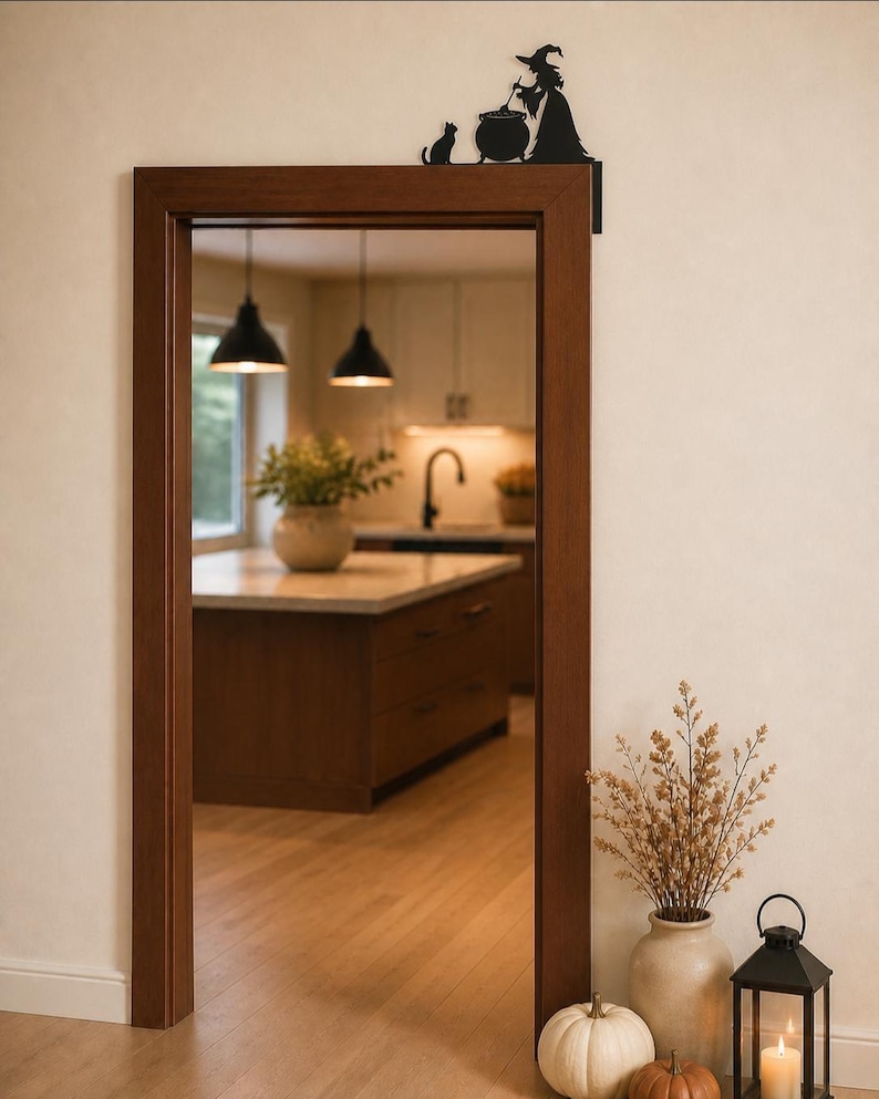 May include: A black metal door corner sign featuring a silhouette of a witch stirring a cauldron with a cat sitting beside it. The decorative piece is mounted on the upper right corner of a wooden door frame, showcasing a flat, cutout design.