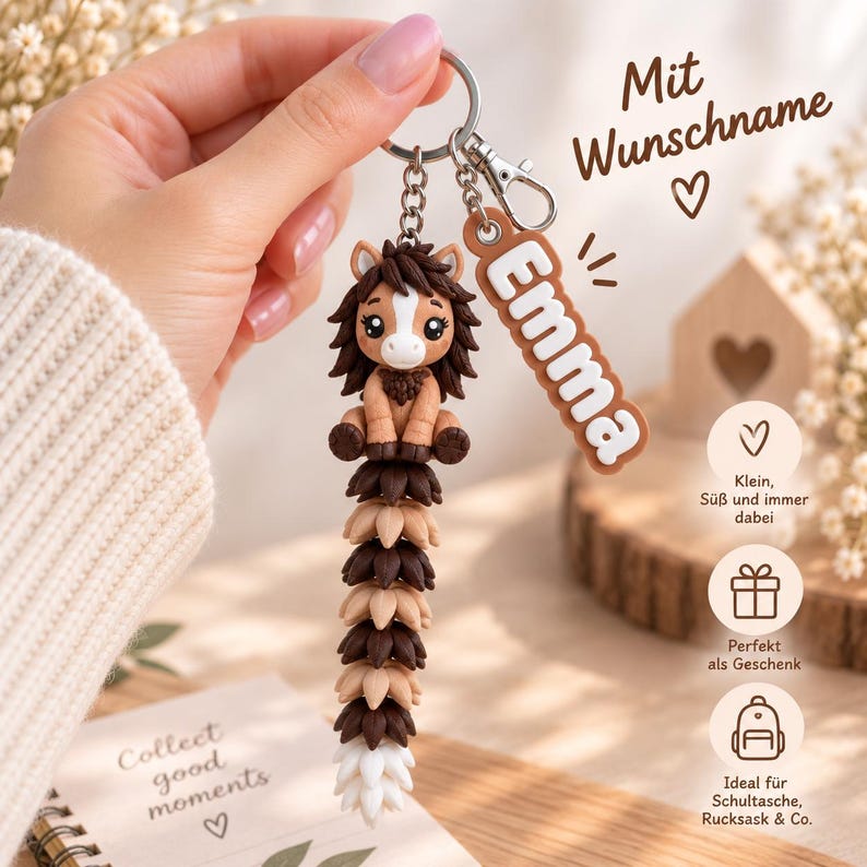 May include: A keychain featuring a brown and tan horse figurine with a long, segmented tail made of alternating dark brown, light brown, and white pieces. A separate rectangular brown tag with the white text Emma is attached to the metal ring.
