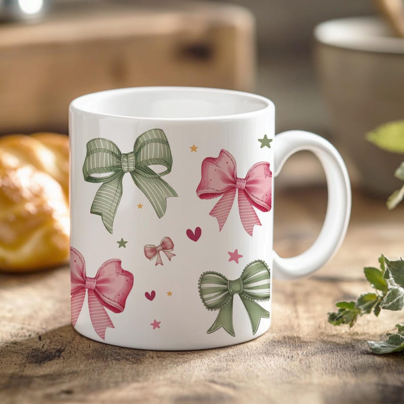 Peut inclure: Une tasse en c&eacute;ramique blanche avec un motif de n&oelig;uds verts et roses. Les n&oelig;uds sont dispos&eacute;s de mani&egrave;re al&eacute;atoire sur la tasse. Il y a aussi de petites &eacute;toiles et des c&oelig;urs sur la tasse.