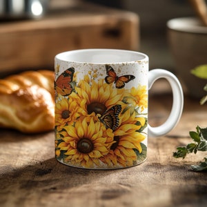 May include: White ceramic mug with a design of sunflowers and butterflies. The mug has a distressed white background with gold accents.