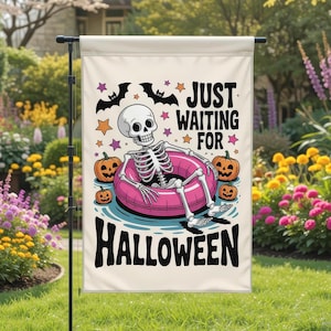 May include: A Halloween garden flag featuring a skeleton in a pink inner tube surrounded by pumpkins. The flag has the text "JUST WAITING FOR HALLOWEEN" in black. Bats and stars decorate the top of the flag.