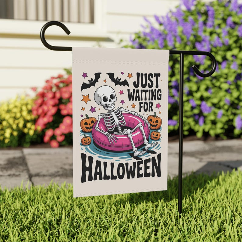 May include: A Halloween garden flag featuring a skeleton relaxing in a pink inner tube. The flag has the text "JUST WAITING FOR HALLOWEEN" with bats, stars, and pumpkins. The flag is displayed on a black metal stand in a grassy yard.