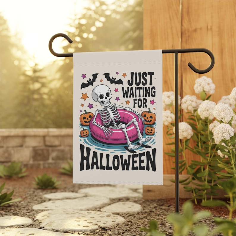 May include: A Halloween garden flag features a skeleton relaxing in a pink inner tube, surrounded by pumpkins. The flag reads "JUST WAITING FOR HALLOWEEN" with bats and stars. The flag is displayed on a black metal stand in a garden setting.