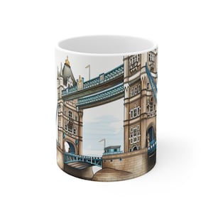 Puede incluir: Taza de cerámica blanca con una ilustración detallada del Tower Bridge de Londres. El diseño presenta la arquitectura del puente en tonos marrón, azul y beige. La taza es de tamaño estándar y tiene un acabado brillante.