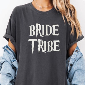 May include: A dark gray t-shirt with the text "BRIDE TRIBE" in white with a lightning bolt graphic.