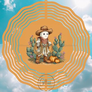 Op de afbeelding: Een grillige, oranje windmolen met een cartoon cowboy karakter met een touw, omringd door cactussen en pompoenen. Het ontwerp is geplaatst tegen een blauwe lucht met wolken en een heldere zon. De spinner heeft een golvende, oranje rand.
