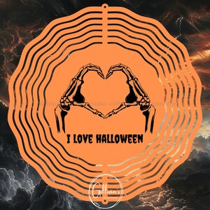 Op de afbeelding: Oranje Halloween-thema decoratie met een skelet hand hartvorm en de tekst "I LOVE HALLOWEEN". Het ontwerp is geplaatst tegen een bewolkte, stormachtige achtergrond. Onderaan staat een cirkelvormig logo.