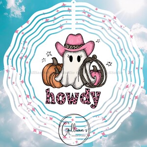Op de afbeelding: Een Halloween-illustratie van een spook met een roze cowboyhoed met een luipaardprintband. Het spook staat naast een oranje pompoen en een lasso met een roze pompoen. Het woord "howdy" is geschreven in roze luipaardprint.