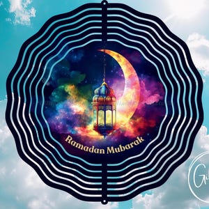 Puede incluir: Un molinillo de viento de metal negro con un diseño colorido de una luna creciente, una linterna y estrellas. El texto "Ramadan Mubarak" está escrito en una pancarta blanca.