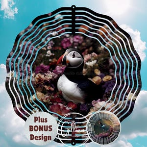 May include: A black metal wind spinner with a circular design featuring a puffin bird surrounded by flowers. The wind spinner has a blue and white color scheme and includes the text "Plus Bonus Design".