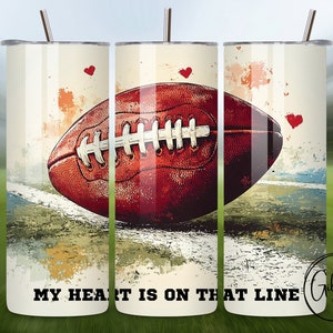 Könnte beinhalten: Ein weißer Becher mit einer braunen und weißen Fußballgrafik und dem Text "My heart is on that line". Der Becher hat eine rote Herzgrafik und einen Aquarellhintergrund.