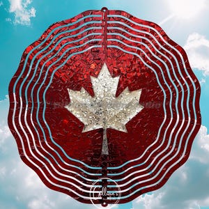May include: A red and white metal wind spinner with a maple leaf design, set against a blue sky with clouds. The maple leaf is silver and the background is red. The wind spinner has a wavy design.