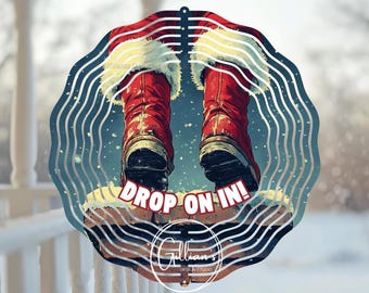 May include: A metal wind spinner with a red and white Santa Claus design. The Santa is falling down a chimney with the text "Drop On In!" on the brick.