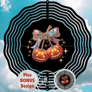 Op de afbeelding: Een zwart-witte windspinner met Halloween-thema met een ontwerp van twee oranje pompoen-kersen met een glinsterende strik. Het ontwerp is omgeven door sterren en een decoratieve rand. Bevat de tekst "Plus BONUS Design" en "Gillian Design Studio".