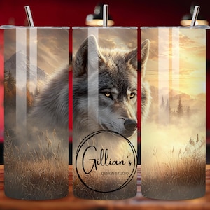 May include: A stainless steel tumbler with a wraparound design featuring a wolf in a misty landscape with mountains and tall grass. The tumbler has a silver straw and the text "Gillian's DESIGN STUDIO".