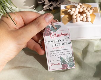 Peut inclure: Une étiquette cadeau blanche avec un motif de Noël rouge et vert. L'étiquette indique "I'm dreaming of a Christmas Simmering Potpourri" avec des instructions d'utilisation et les mots "With Love, Hassata".