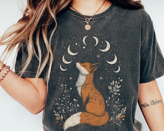 May include: A dark gray t-shirt with a graphic of a fox looking up at a crescent moon and stars. The fox is orange and brown with a white chest. The moon and stars are white. The shirt has a distressed look.